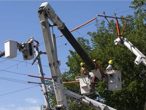 Workers with Saskatoon Light and Power work on getting a new power pole operational at the intersection of Victoria Avenue and 7th Street in Saskatoon July 17, 2013.