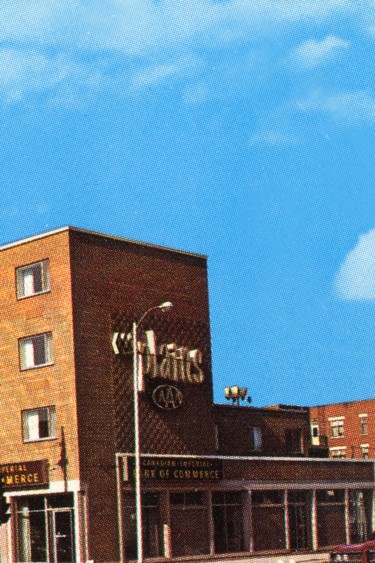 A postcard showing the Plains Hotel in 1970, seen from the corner of Albert Street and Victoria Avenue, and displaying the words "under the weather tower."