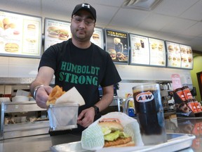 HUMBOLDT, SK - A&W employee Vishal Vansal serves a free meal with a donation to help people affected in the Humboldt Broncos bus crash, while wearing a 'Humboldt Strong' shirt in Humboldt, Sask., on April 10, 2018.