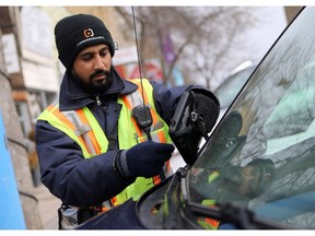 A parking enforcement staff member for the city of Saskatoon prints out a ticket for a vehicle parked downtown in Saskatoon on April 26, 2017.