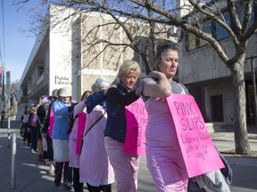 Protestors wearing pink slip dress, to represent lay-off notices given to Saskatoon Public Library (SPL) workers, walk from the Frances Morrison Library to City Hall during a organized protest to recent budget cuts at the SPL in Saskatoon, SK on Monday, April 30, 2017.