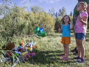 Khloie and Karlie Erdman stand around a makeshift memorial by Dundonald School after a five-year-old died in a nearby pond in Saskatoon, SK on Tuesday, September 12, 2017.