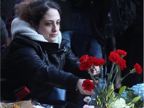 A woman places carnations before a vigil at a makeshift memorial in Mel Lastman Square in Toronto for the victims of the van attack before a vigil on April 29, 2018.