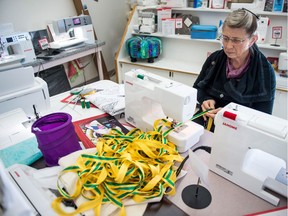 Peggy Gwillim sits in sewing supplies store Haus of Stitches on April 13, 2018, cutting ribbon in the colours of the Humboldt Broncos at the request of the Saskatchewan Volunteer Firefighters Association. Many in Humboldt and elsewhere are wearing the ribbons as a sign of acknowledgement and support. The store ran out of ribbon following the collision that left many members of the hockey team dead. However, the store recently received a shipment of 600 metres in both green and gold and plans to continue supplying ribbons to the community as needed.