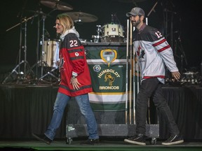 Olympian Hayley Wickenheiser, left,places a hockey stick on a Humboldt Broncos jersey during the Country Thunder Humboldt Broncos tribute concert in Saskatoon, Sask. Friday, April 27, 2018.