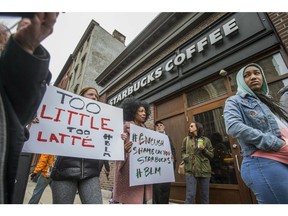 Protesters gather outside of a  Starbucks in Philadelphia, Sunday, April 15, 2018, where two black men were arrested Thursday after employees called police to say the men were trespassing. The arrest prompted accusations of racism on social media. Starbucks CEO Kevin Johnson posted a lengthy statement Saturday night, calling the situation "disheartening" and that it led to a "reprehensible" outcome.  (Michael Bryant/The Philadelphia Inquirer via AP) ORG XMIT: PAPHQ702