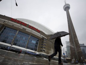 A man walks by the Rogers Centre as reports of falling ice from the CN Tower sparked a closure of parts of the area on Toronto on Monday, April 16, 2018.