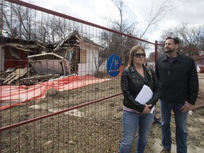 Shannon Vinnish (L) and Daniel Gerle stand outside a home at the corner of Avenue B and 34th Street that has been left partly demolished with asbestos warnings, Wednesday, April 25, 2018.