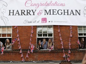 Royal fans lean out of windows as they watch Britain's Prince Harry and his best man Prince William, Duke of Cambridge, greet well-wishers on the street outside Windor Castle in Windsor on May 18, 2018, the eve of Prince Harry's royal wedding to US actress Meghan Markle.  Britain's Prince Harry and US actress Meghan Markle will marry on May 19 at St George's Chapel in Windsor Castle.