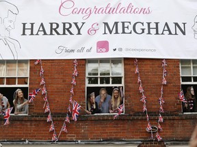 Royal fans lean out of windows as they watch Britain's Prince Harry and his best man Prince William, Duke of Cambridge, greet well-wishers on the street outside Windor Castle in Windsor on May 18, 2018, the eve of Prince Harry's royal wedding to US actress Meghan Markle.  Britain's Prince Harry and US actress Meghan Markle will marry on May 19 at St George's Chapel in Windsor Castle.