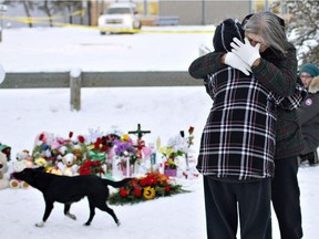 Residents console each other at the memorial near the La Loche Community School in La Loche, Sask., on Sunday, January 24, 2016.