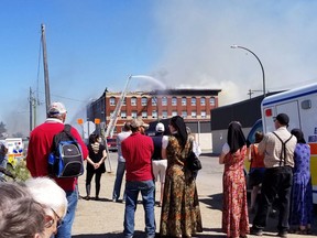 People look on as fire crews control a blaze in downtown Brandon, Man., on Satuurday May 19, 2018. A blaze that Premier Brian Pallister called "massive" has burned through several buildings in downtown Brandon, Man., including one with dozens of apartments managed by community groups.