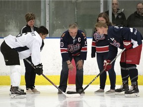 Russ Herold drops the puck during the ceremonial faceoff before a benefit hockey game Friday night at the Co-operators Centre. Herold is flanked by his wife Raelene, left, and daughter Erin. Taking the faceoff are Alex Kannok Leipert, left, and Drew Englot.