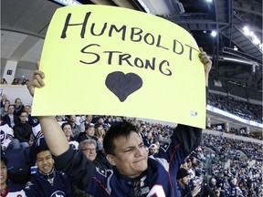 Rance Cardinal holds up a sign remembering the Humboldt Broncos bus crash victims during the Winnipeg Jets and Chicago Blackhawks NHL game in Winnipeg on Saturday, April 7, 2018.