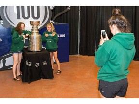 Taylor Standish, centre, and Abby Corney are photographed by Hanna Bailey next to the Stanley Cup at Evraz Place on Wednesday. The Cup was in Regina as part of the 100th anniversary of the Memorial Cup.