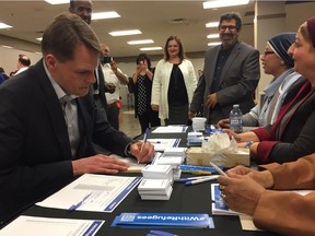 Mayor Charlie Clark signs the United Nations #WithRefugees petition at the Open Door Society's WEconnect job fair at TCU Place in Saskatoon on May 3, 2018. (Erin Petrow/Saskatoon StarPhoenix)