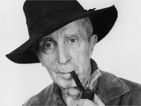 Studio headshot portrait of American painter Norman Rockwell (1894 - 1978) smoking a pipe while wearing a floppy felt hat.