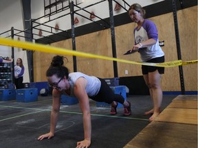 Bruce Gordon's daughter Jillian Bodnar (left) competes in the Be Life Bruce Fitness Festival to honour his memory while Bruce's wife Chris Gordon (right) acts as a judge at the Reebok CrossFit 306 gym in Saskatoon on June 9.