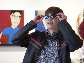 Balloons are reflected in Alex Leveille's lenses, as he tries on a pair of EnChroma glasses that assist colour-blind people to see colours.