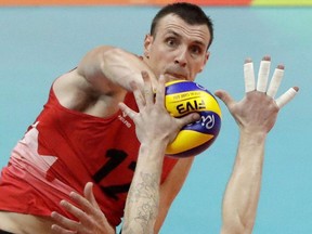 Canada's Gavin Schmitt spikes the ball as Italy's Ivan Zaytsev blocks during a men's preliminary volleyball match at the 2016 Summer Olympics in Rio de Janeiro, Brazil, Monday, Aug. 15, 2016. Gavin Schmitt doesn't want his return to the national men's volleyball team to interfere with the team's success. He says Canada, currently ranked sixth in the world, has been doing just fine without him.