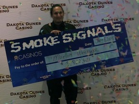 Marlon Weekusk holds his cheque for more than $1.8 million after winning the Smoke Signals jackpot at Dakota Dunes Casino on June 6, 2018.