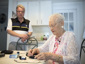 Petronella Hofenk tests her blood sugar level as her son Rick looks on in Regina on June 6, 2018. The Hofenks are upset with a 2015 change to the drug plan that limits the number of blood glucose test strips that are covered under the provincial drug plan.
