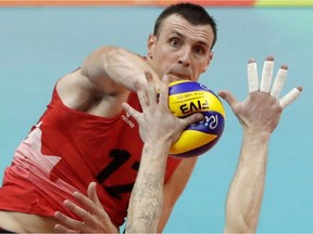 Canada's Gavin Schmitt spikes the ball as Italy's Ivan Zaytsev blocks during a men's preliminary volleyball match at the 2016 Summer Olympics in Rio de Janeiro, Brazil, Monday, Aug. 15, 2016. Gavin Schmitt doesn't want his return to the national men's volleyball team to interfere with the team's success. He says Canada, currently ranked sixth in the world, has been doing just fine without him.