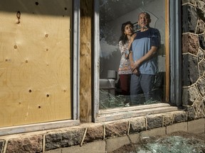 Abu Sheikh, right, is seen with his daughter Aisha through his broken front window which was shattered on July 13, 2018, when he says a man attacked him with a truck and threw bricks at his home.
