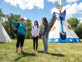 Florence Lalonde, centre, and Charlotte Caron, right, women on an exchange program from Quebec, listen as the woman who is hosting them in Saskatchewan speaks about the teepees at the Justice for our Stolen Children camp across from the Saskatchewan Legislative Building.