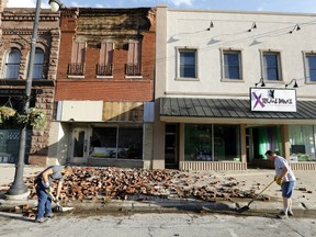 Workers clean up bricks from a tornado-damaged business on Main Street, Thursday, July 19, 2018, in Marshalltown, Iowa. Several buildings were damaged by a tornado in the main business district in town including the historic courthouse.