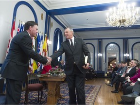 Gordon Wyant, left, and Don Morgan, center, shake hands during a swearing in ceremony held at Government House. Wyant was appointed deputy premier and education minister; Morgan remained justice minister and attorney general among other portfolios.