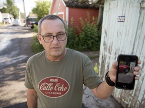 Richard Reid holds up his cellphone to display a photo he got of his stolen vehicle that ended up crashed into this garage in the alley of the 2200 block between Halifax Street and Osler Street in Regina.