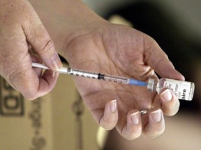 A nurse loads a syringe with vaccine for injection.
