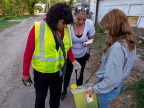 White Pony Lodge Patrol Coordinator Leticia Racine, left, and volunteers examine a knife found in a North Central alleyway as the organization carries out a search for harmful objects on one of the organization's routine neighbourhood patrols.
