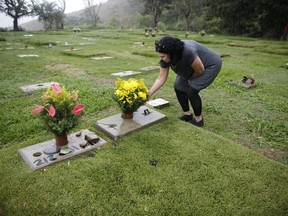 In this July 1, 2018 photo, Ivonne de Gutierrez visits the Cemetery of the East where her son, nephew and aunts are buried in Caracas, Venezuela. Gutierrez says the headstones marking the graves of her nephew and two aunts have disappeared, and that so far looters have skipped over her son's headstone.