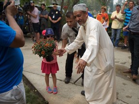 Six-year-old Louise Bakker (left) and Abu Sheikh (right) go to plant flowers in front of Sheikh's home as part of the solidarity walk on August 11, 2018, supporting Sheikh after he reported being attacked in July.