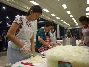 Marissa Oliver (left) chops onions at the Folkfest Philippines pavilion on Wednesday, August 15 in preparation of Folkfest opening on Thursday night.