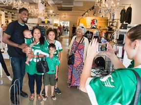 Duron Carter has his photo taken with fan Hoy Hill, next to Carter, who is holding her child Hudson Hill and accompanied by her children Riley Hill, in front, and Josie Hill at the Coda/Cade store on Albert Street. BRANDON HARDER/ Regina Leader-Post