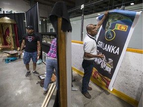Thushan Withana-Gamage, right, with the Sri Lanka Association of Saskatchewan Inc. hangs a posters at the new Sri Lanka Folkfest pavilion at Archibald Arena in Saskatoon, SK on Thursday, August 16, 2018.