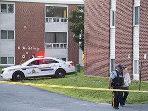 An RCMP officer and a resident carry a pet container from an evacuated apartment building in Fredericton on Friday, August 10, 2018. Two city police officers were among four people who died in a shooting in the residential area on the city's north side.