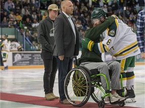 Humboldt Broncos  forward Reagan Poncelet, right hugs, bus survivor Jacob Wassermann as former humboldt assistant coach, and survivor, Scott Barney looks on prior to the Broncos home opener game against the Nipawin Hawks in Humboldt, SK on Wednesday, September 12, 2018.