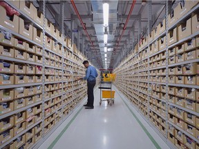 An employee of Amazon India retrieves products from an assorted storage area to fulfil orders placed by customers prior to packaging at an Amazon's newly launched Fulfilment Centres (FCs) situated in the suburban area of Bangalore on September 18, 2018. - The US online retail Fulfilment Centres (FCs) in Karnataka is spread over 350,000 square feet and close to 2 million cubic feet of storage space.