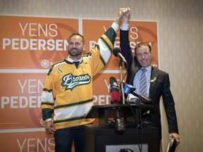 NDP party leader Ryan Meili, left, holds up the hand of Yens Pedersen as he won the Regina Northeast byelection and celebrated the victory in Regina on Sept. 12, 2018.