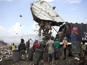 In this Aug. 23, 2018 photo, Changlair Aristide, in red shirt at centre, waits for a truck to finish dumping its load at the Truitier landfill in the Cite Soleil slum of Port-au-Prince, Haiti.