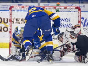 Saskatoon Blades goalie Dorrin Luding stops a shot as defence Brandon Schuldhaus knocks over Calgary Hitmen forward Josh Prokop during first-period WHL action at SaskTel Centre in Saskatoon on Wednesday, October 17, 2018.