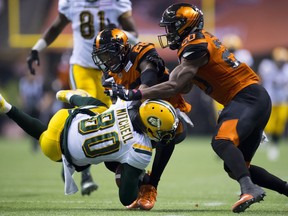 BC Lions defensive back Anthony Orange (26) and BC Lions linebacker Bo Lokombo (20) stop Edmonton Eskimos wide receiver Bryant Mitchell (80) during CFL football action in Vancouver, B.C., on Friday, Oct. 19, 2018.
