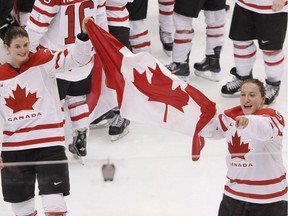 Team Canada players Gina Kingsbury, left, and Colleen Sostorics celebrate with the flag after winning the gold medal ice hockey game against Team USA at the Vancouver 2010 Olympics Feb. 25, 2010. The changes in women's hockey since Jacques Rogge threatened to kick it out of the Winter Olympics will be felt in Sochi, albeit subtly.