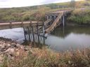 Un pont effondré est vu dans la municipalité régionale de Clayton sur une photo du mardi 18 septembre 2018.  La municipalité de la Saskatchewan, où un pont nouvellement construit s'est effondré quelques heures après l'ouverture, avait reçu un financement provincial de 750 000 $ pour la construction, mais a opté pour une conception moins coûteuse, a déclaré un dirigeant rural.  Le pont commémoratif Dyck dans la municipalité rurale de Clayton a été ouvert à la circulation le 14 septembre, mais s'est effondré dans la rivière Swan plus tard dans la journée.  Personne n'a été blessé et l'entrepreneur est responsable des réparations.