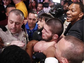 Khabib Nurmagomedov, bottom center, is held back outside of the cage after fighting Conor McGregor in a lightweight title mixed martial arts bout at UFC 229 in Las Vegas, Saturday, Oct. 6, 2018. Nurmagomedov won the fight by submission during the fourth round to retain the title.