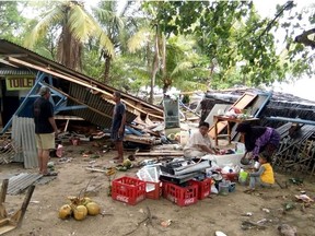 People gather salvageable items from damaged buildings on Carita beach on December 23, 2018, after the area was hit by a tsunami that may have been caused by the Anak Krakatoa volcano.